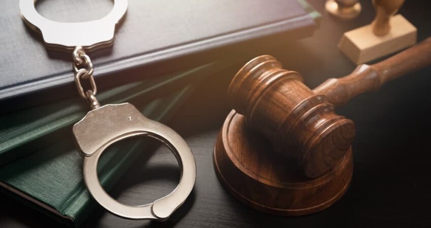 gavel on table next to handcuffs and law books